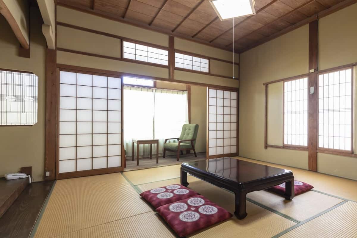 Une pièce de style japonais traditionnel, avec un sol recouvert de tatamis, des portes coulissantes et une table basse.