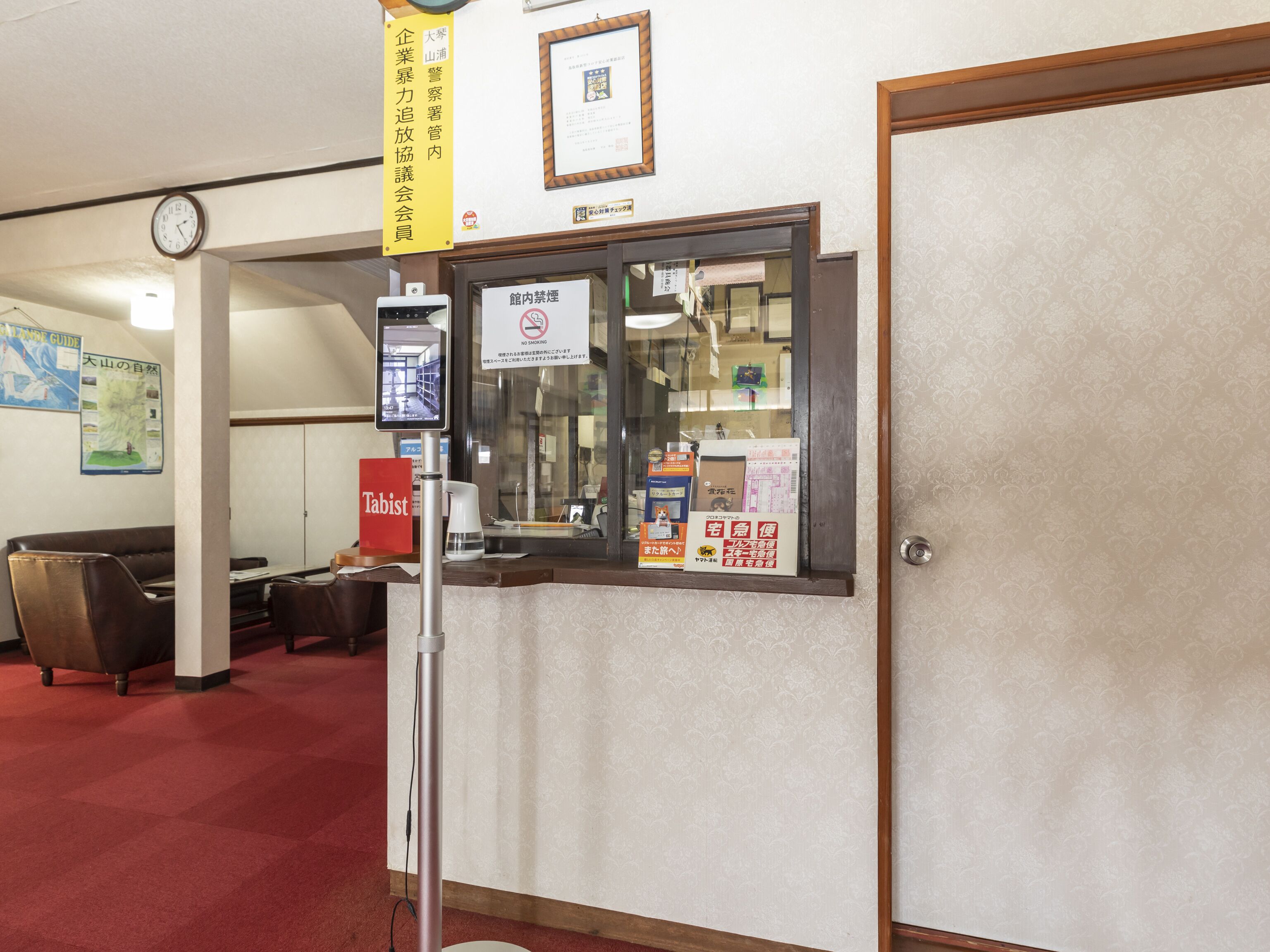 A reception area with a glass display case, a clock, a 'Tabist' sign, and a 'No Smoking' sign.