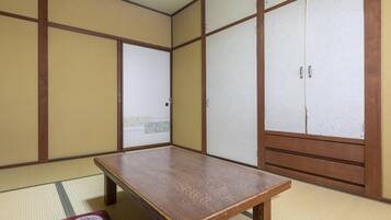 Een traditionele Japanse kamer met tatami vloerbedekking, een houten tafel, glijdende deuren en uitzicht door een raam.
