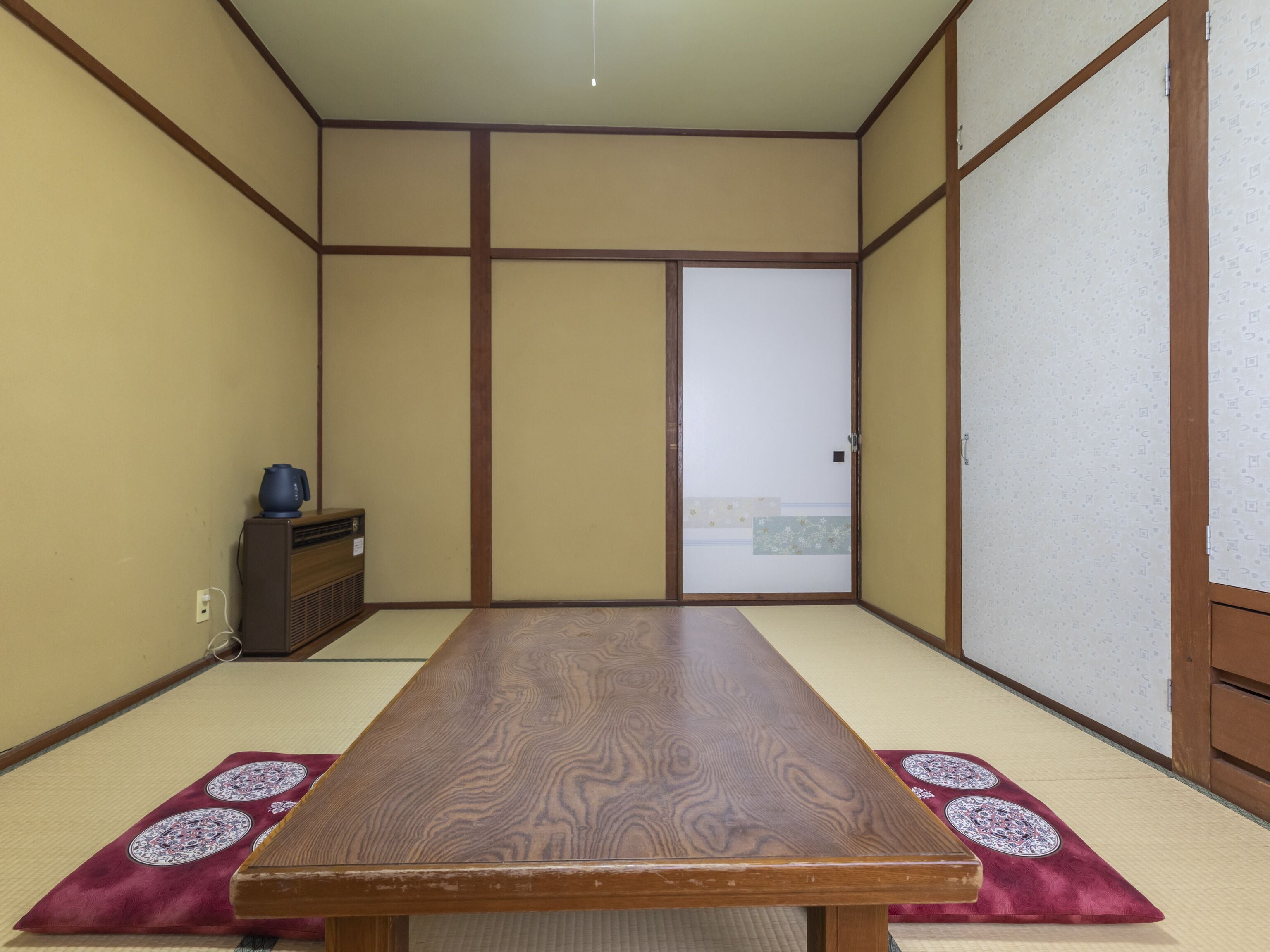 Una habitación japonesa tradicional con suelo de tatami, una mesa de madera y puertas correderas.