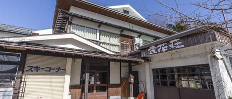 A two-story building with a traditional Japanese architectural style, featuring a wooden facade and a sloped roof.