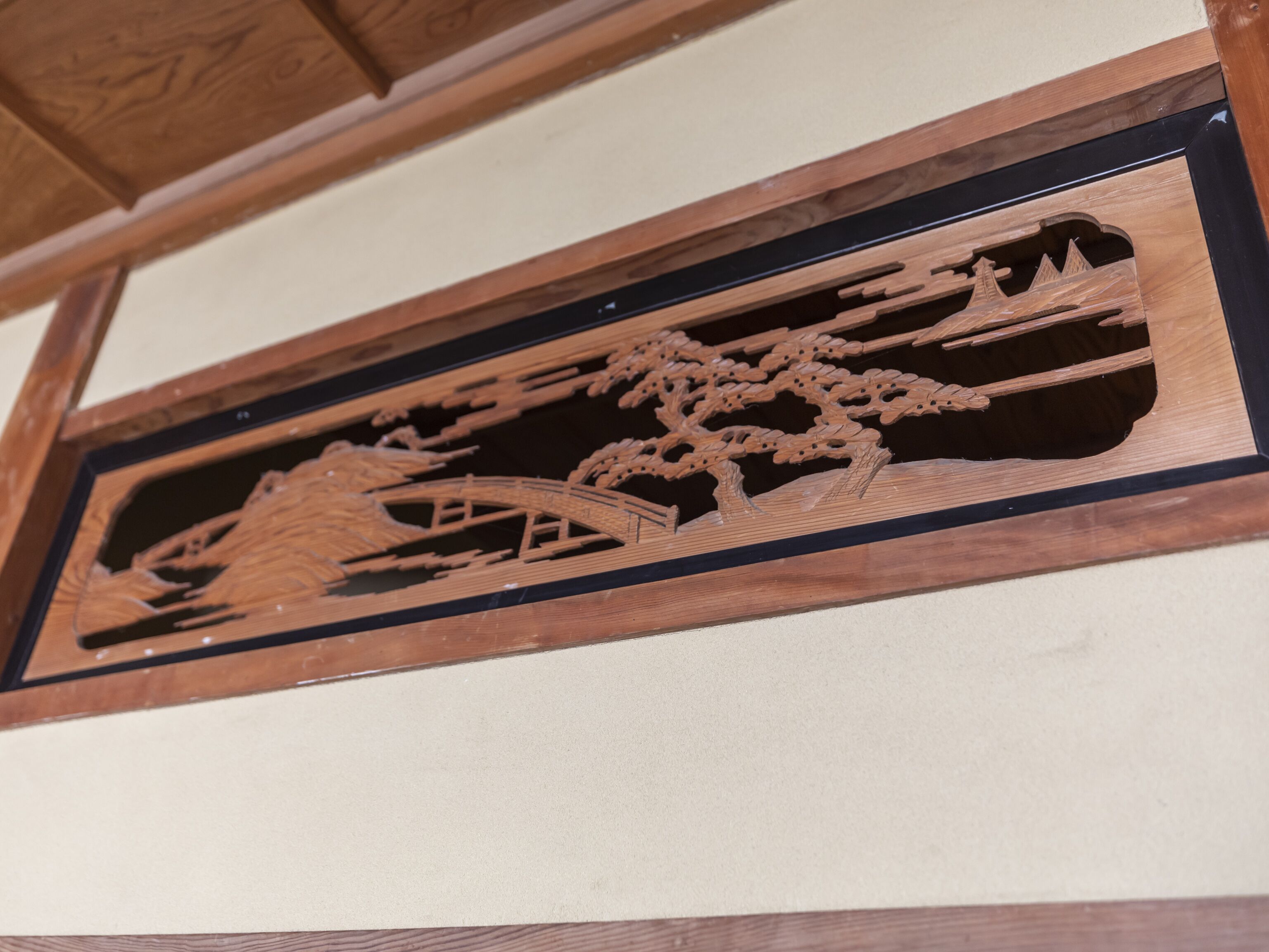 A detailed wooden carving of a bridge and trees.