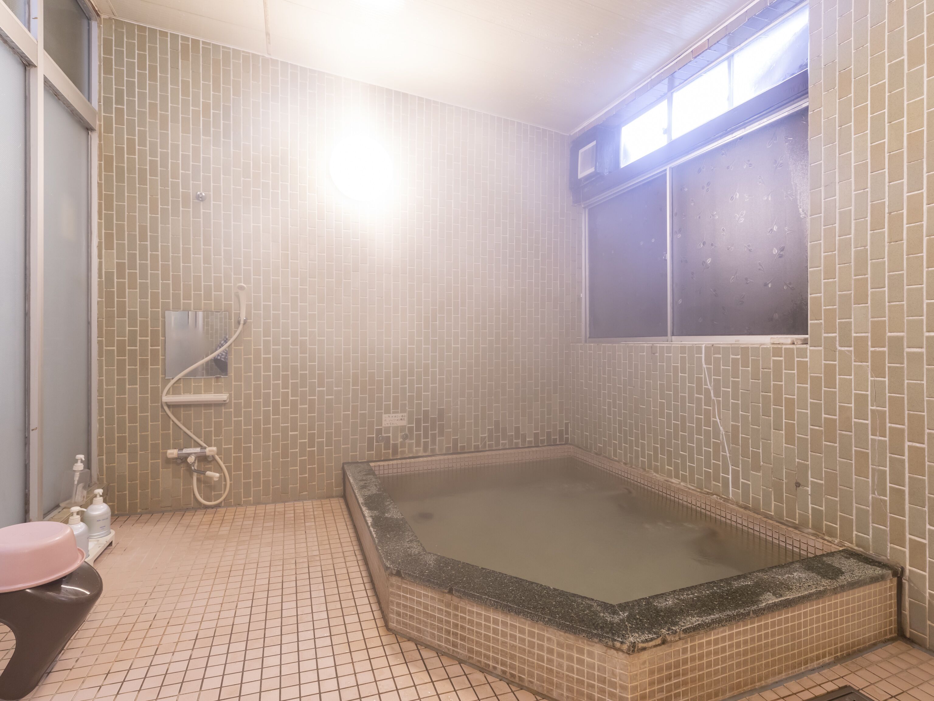 A bathroom with a large bathtub, a window, and tiled walls.