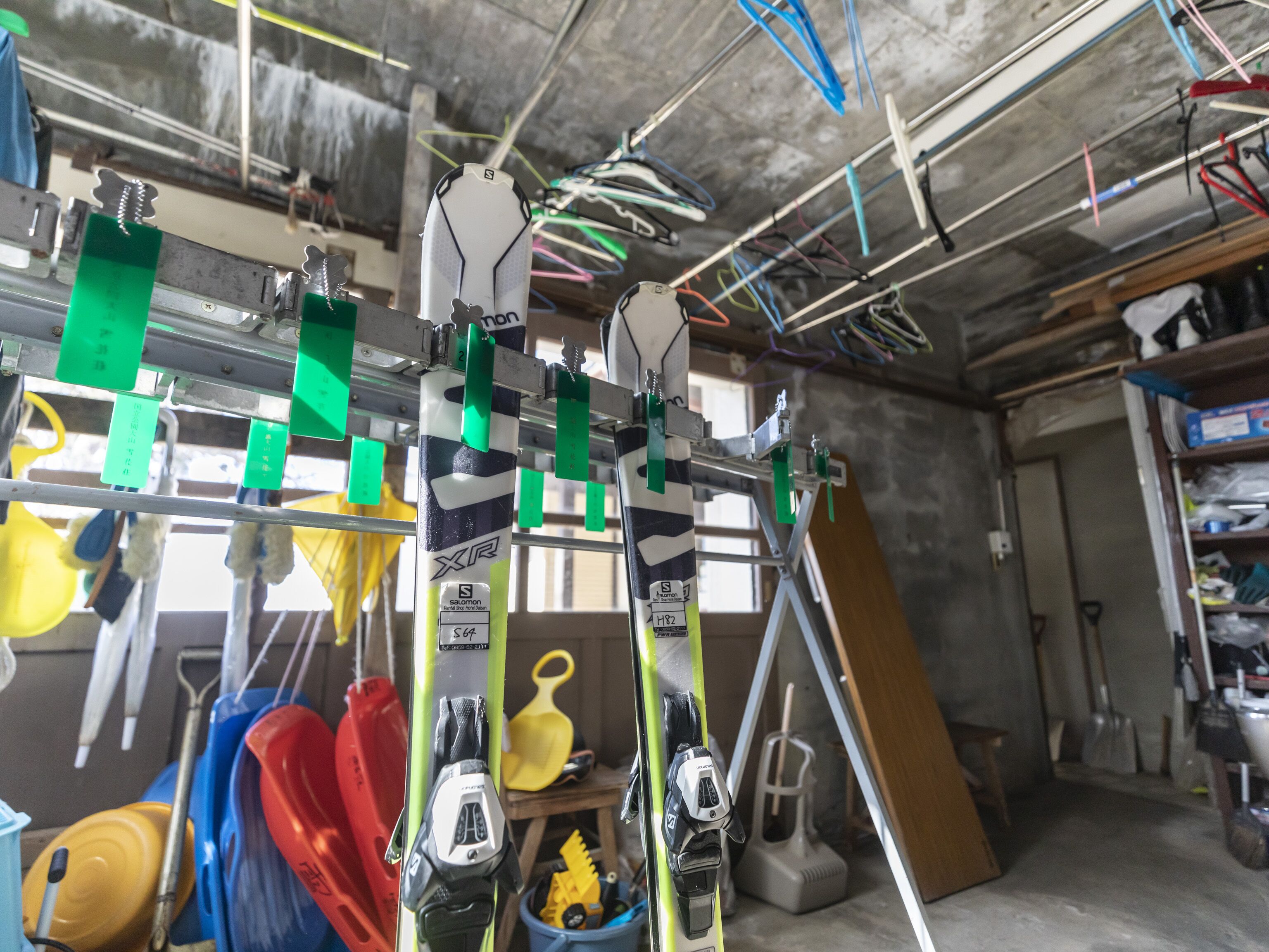 A garage with various tools and equipment, including a workbench, shelves, and hanging items.