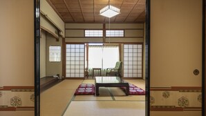 A traditional Japanese room with tatami flooring, a low table, a green chair, and sliding doors. - Tabist Sekkasou (Daisen)