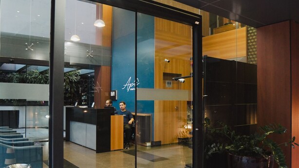 A reception area with a glass partition, a reception desk, and a seating area with a potted plant.