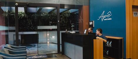 A reception area with a glass door entrance, a reception desk, and a blue wall with the logo "Ape smart studios".