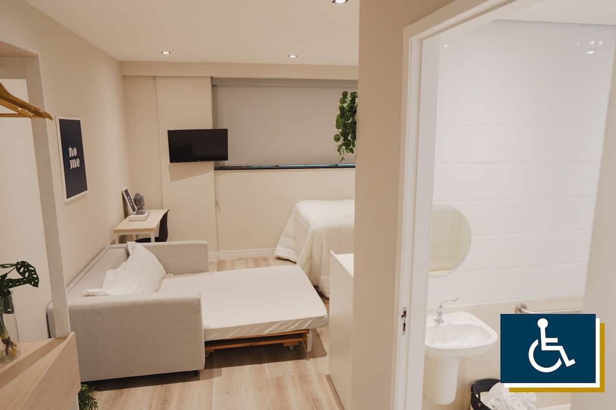 Una habitación de hotel moderna con una cama, mesita de noche y televisión.