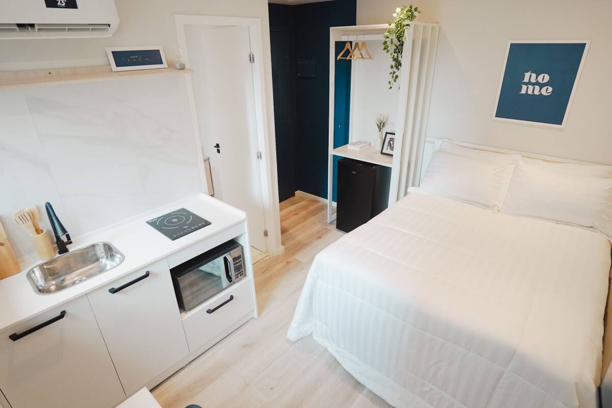 Una habitación compacta con cama, una kitchenette pequeña y una puerta que da a un baño.