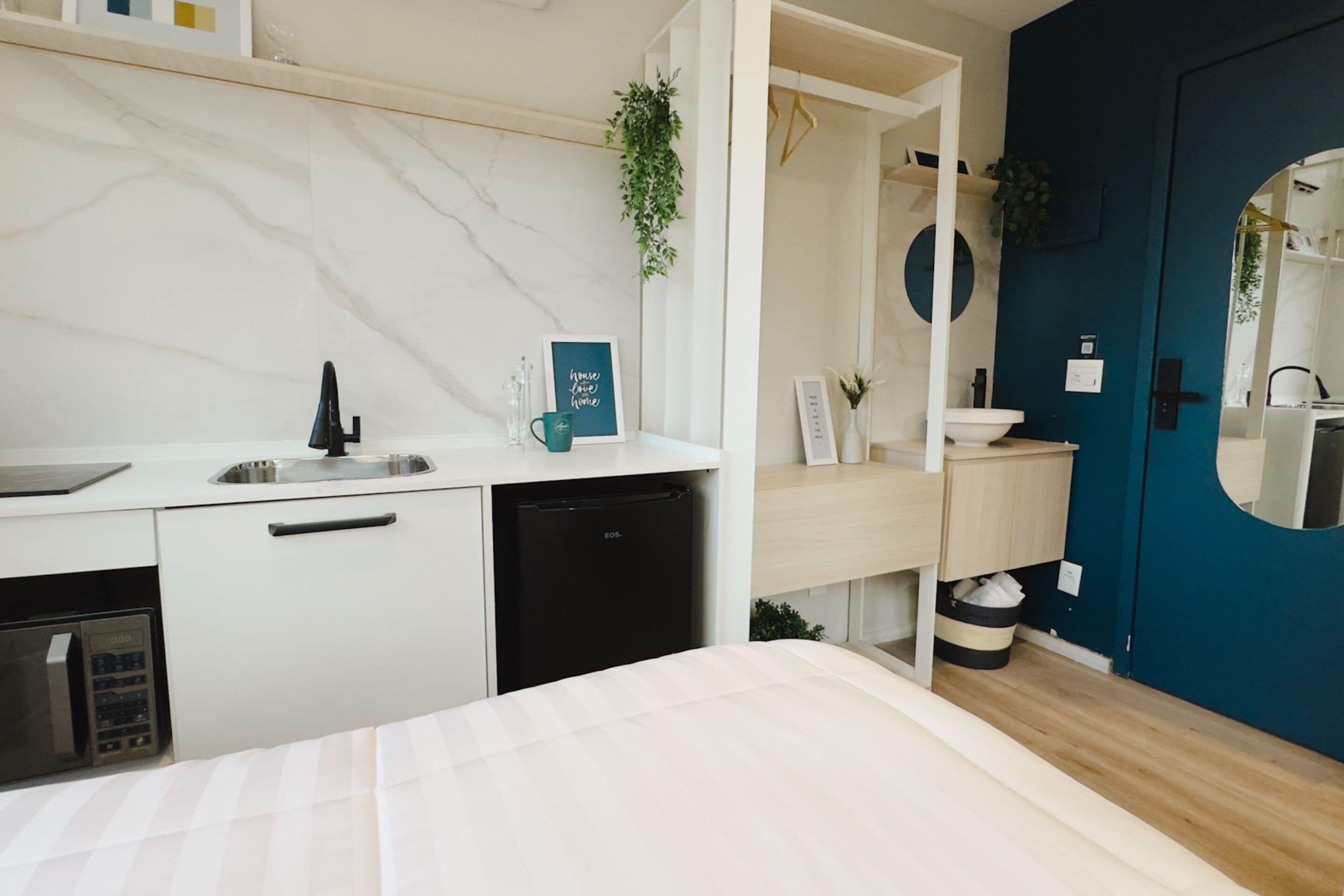A modern bathroom with a white sink, black faucet, and a blue door.
