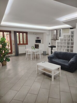 A modern living room with a dining area, a sofa, and a potted plant.