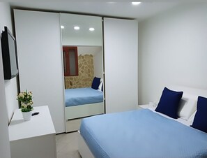 Relax in a serene bedroom with a large bed, bedside table, and wardrobe, set against a stone accent wall.