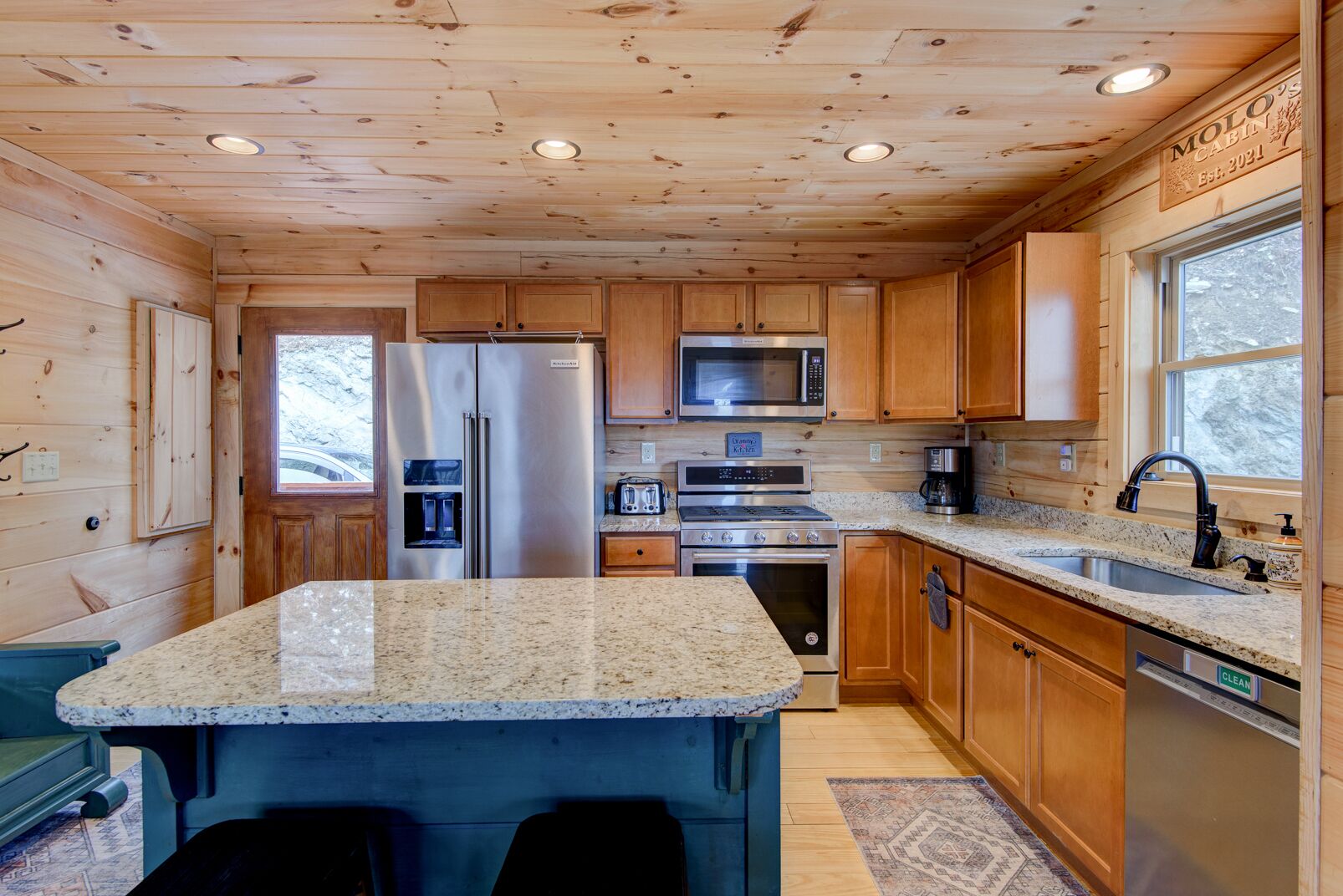 A modern kitchen with wooden cabinets, stainless steel appliances, granite countertops, and a built-in island.