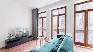 A modern living room with a teal sofa, a flat-screen TV, and a small table. - GuestReady - Almada 516 (Porto)