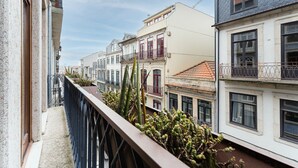 A narrow street with buildings on either side, featuring balconies with metal railings and some vegetation. - GuestReady - Almada 516 (Porto)