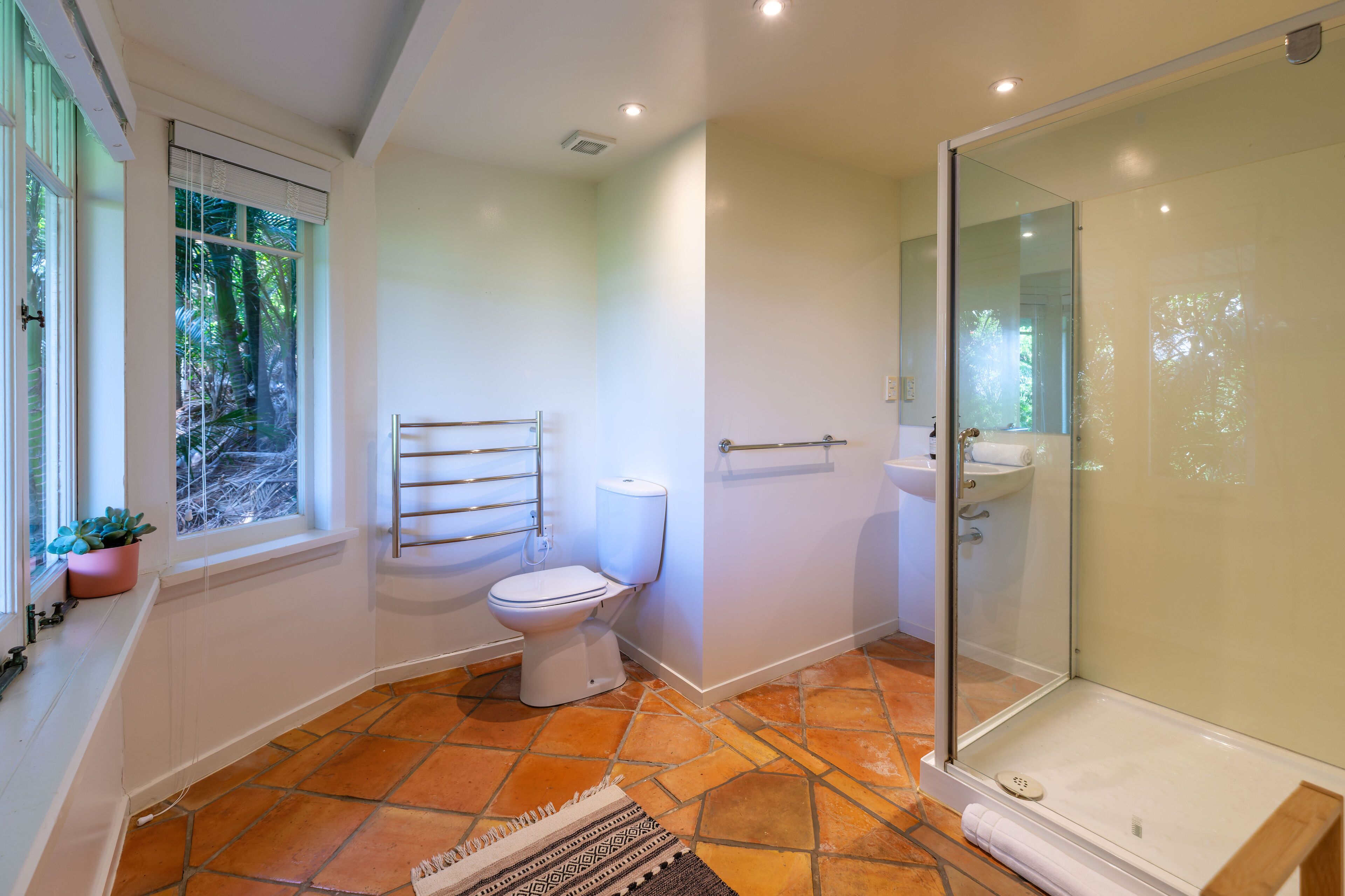 A modern bathroom with a toilet, shower, and sink.