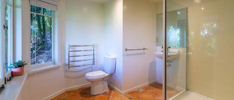 A modern bathroom with a toilet, shower, and sink.