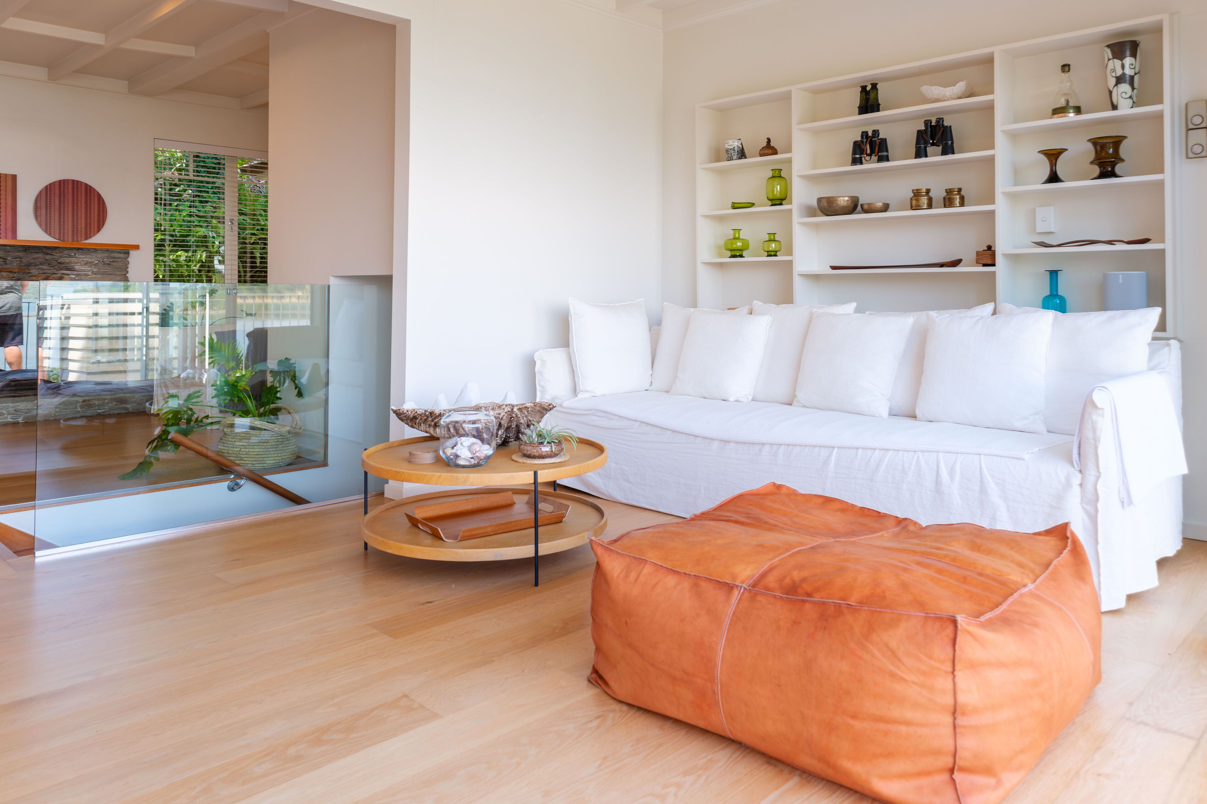 Un salon moderne avec un canapé blanc, une table basse en bois et une cloison en verre.