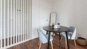 A modern room with a round table, two chairs, a mirror, and a wicker basket. - GuestReady - Almada 516 (Porto)