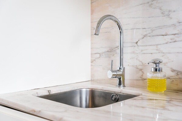 A kitchen sink with a modern faucet and a soap dispenser on the countertop.