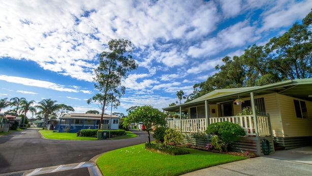 A residential street with houses, a grassy lawn, and a clear sky. - Shoalhaven Heads Village (Shoalhaven Heads)