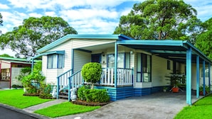 A two-story mobile home with a porch, a small front yard, and a satellite dish. - Shoalhaven Heads Village (Shoalhaven Heads)