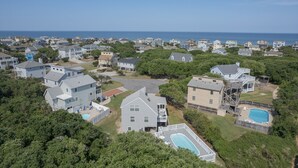 A residential area with houses, a swimming pool, and a view of the ocean. - 4002 - Duffy Duck - Heart of Duck Escape w/ Pool & Hot Tub (Duck)