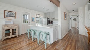 A kitchen with a central island, bar stools, a microwave, and a refrigerator. - 4002 - Duffy Duck - Heart of Duck Escape w/ Pool & Hot Tub (Duck)