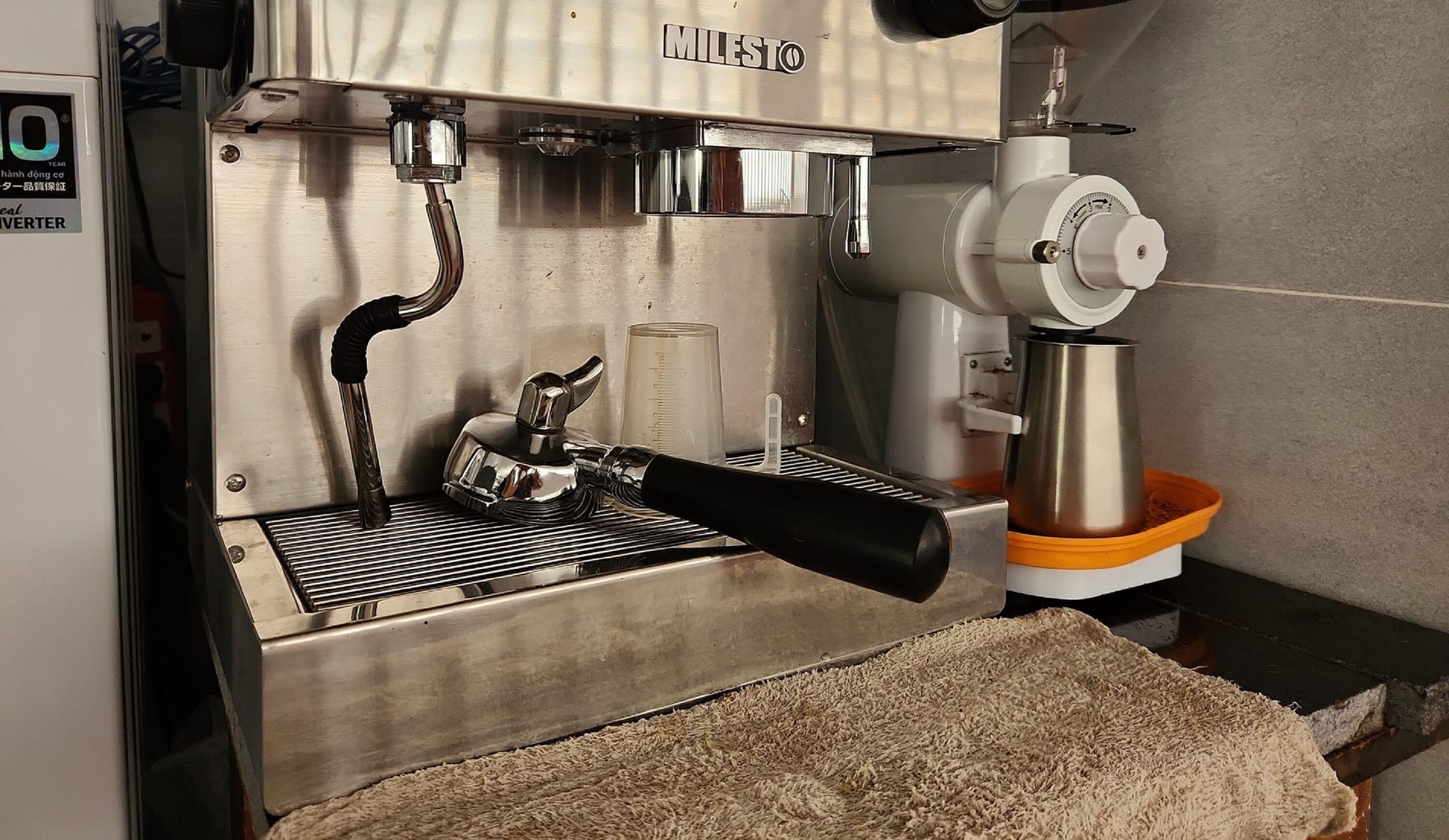 Eine Kaffeemaschine mit Auffangbehälter, Milchaufschäumer und Siebträger.