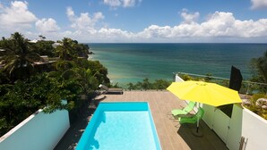 A rooftop pool with a view of the ocean, surrounded by greenery and a yellow umbrella. - VILLA VICTORIA FACING THE SEA (Le Gosier)