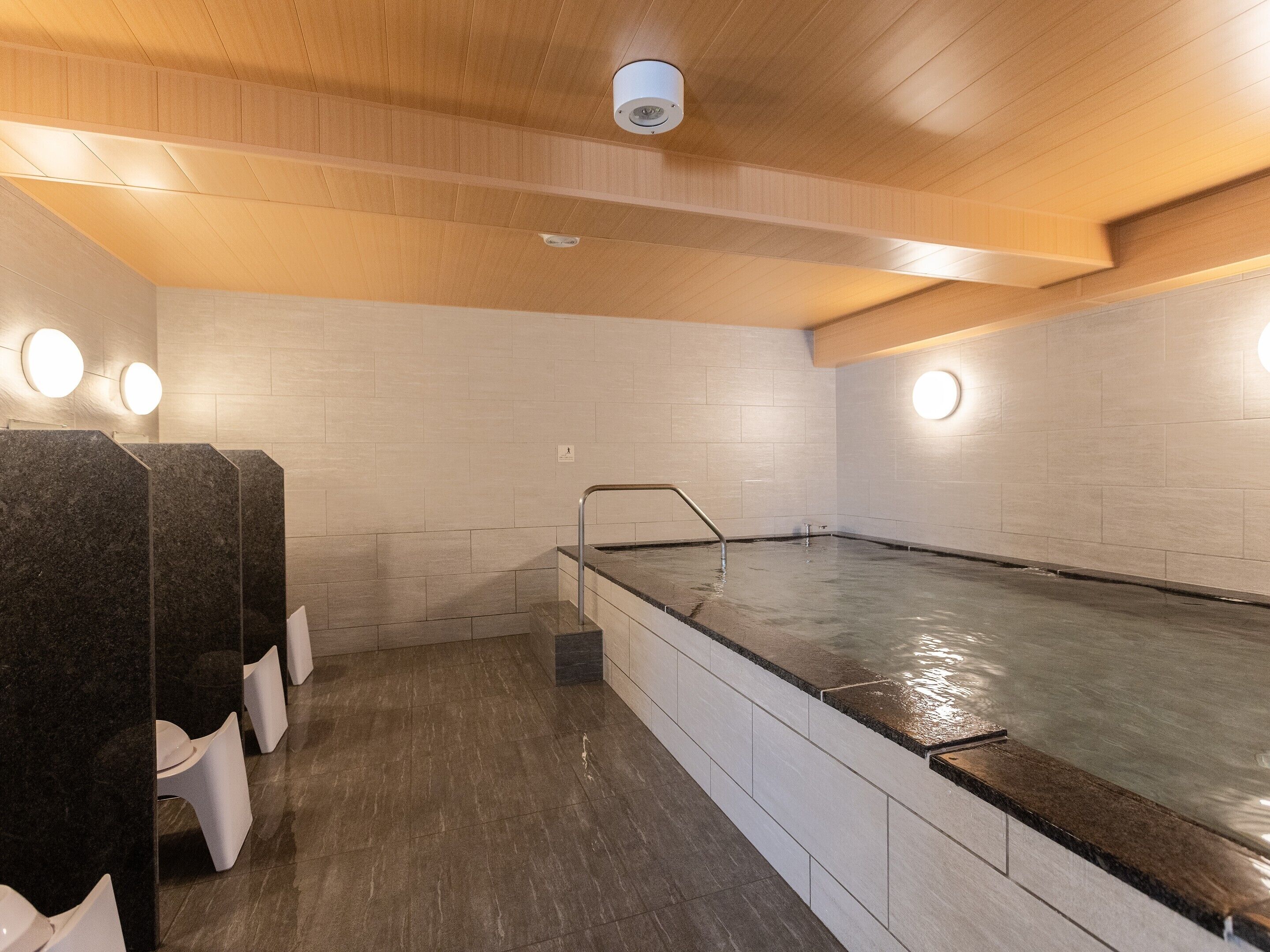 Un espace spa comprenant un jacuzzi, des sièges en marbre et un plafond en bois.