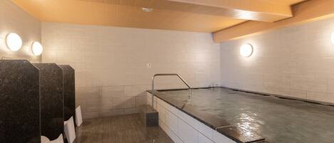 Un área de spa con jacuzzi, asientos de mármol y techo de madera.