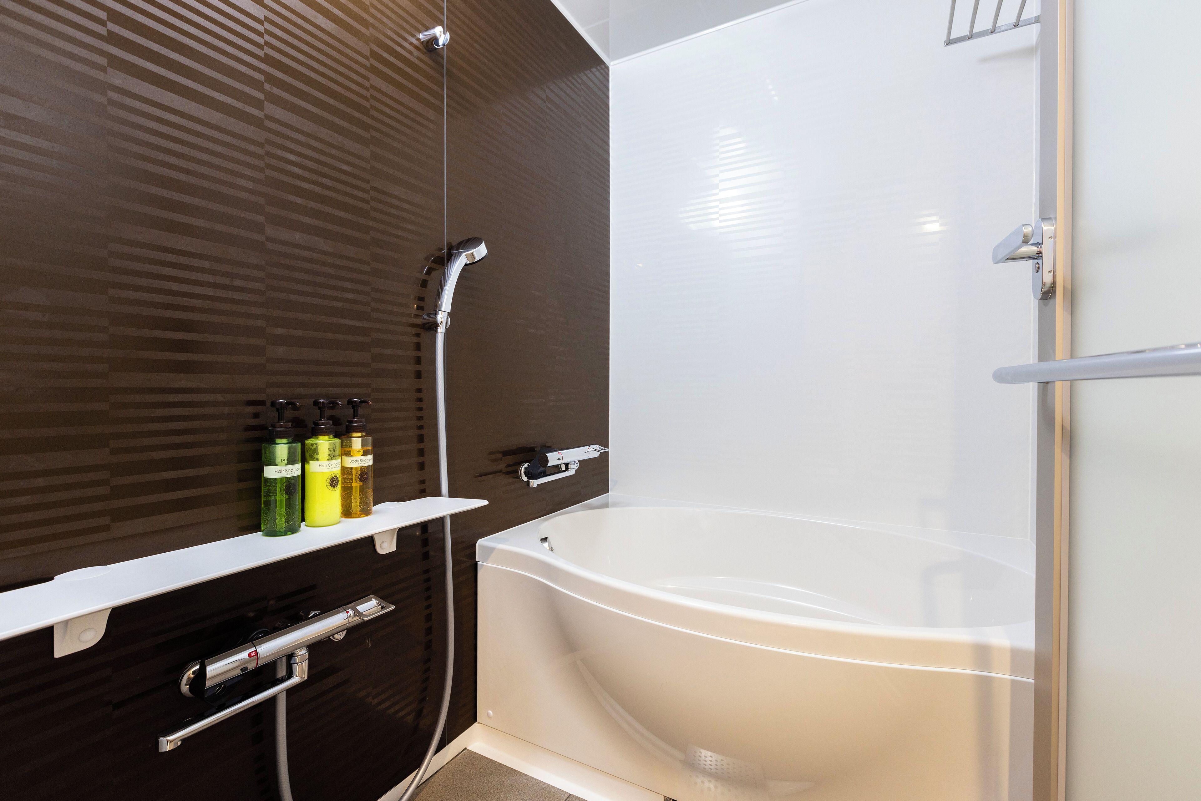A modern bathroom with a bathtub, a shower, and a shelf with toiletries.