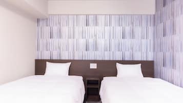 A hotel room with two beds, a wooden headboard, and a striped wall design.