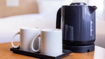 Una tetera eléctrica negra y dos tazas blancas sobre una bandeja.