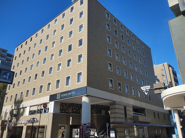 Un hotel de varios pisos con fachada de ladrillo moderno, una entrada visible y un letrero que indica que es un Koko Hotel.