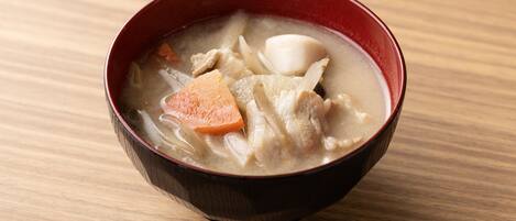 A bowl of soup with various ingredients on a wooden surface.