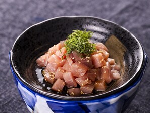 Un bol de sashimi con semillas de sésamo y guarnición verde.