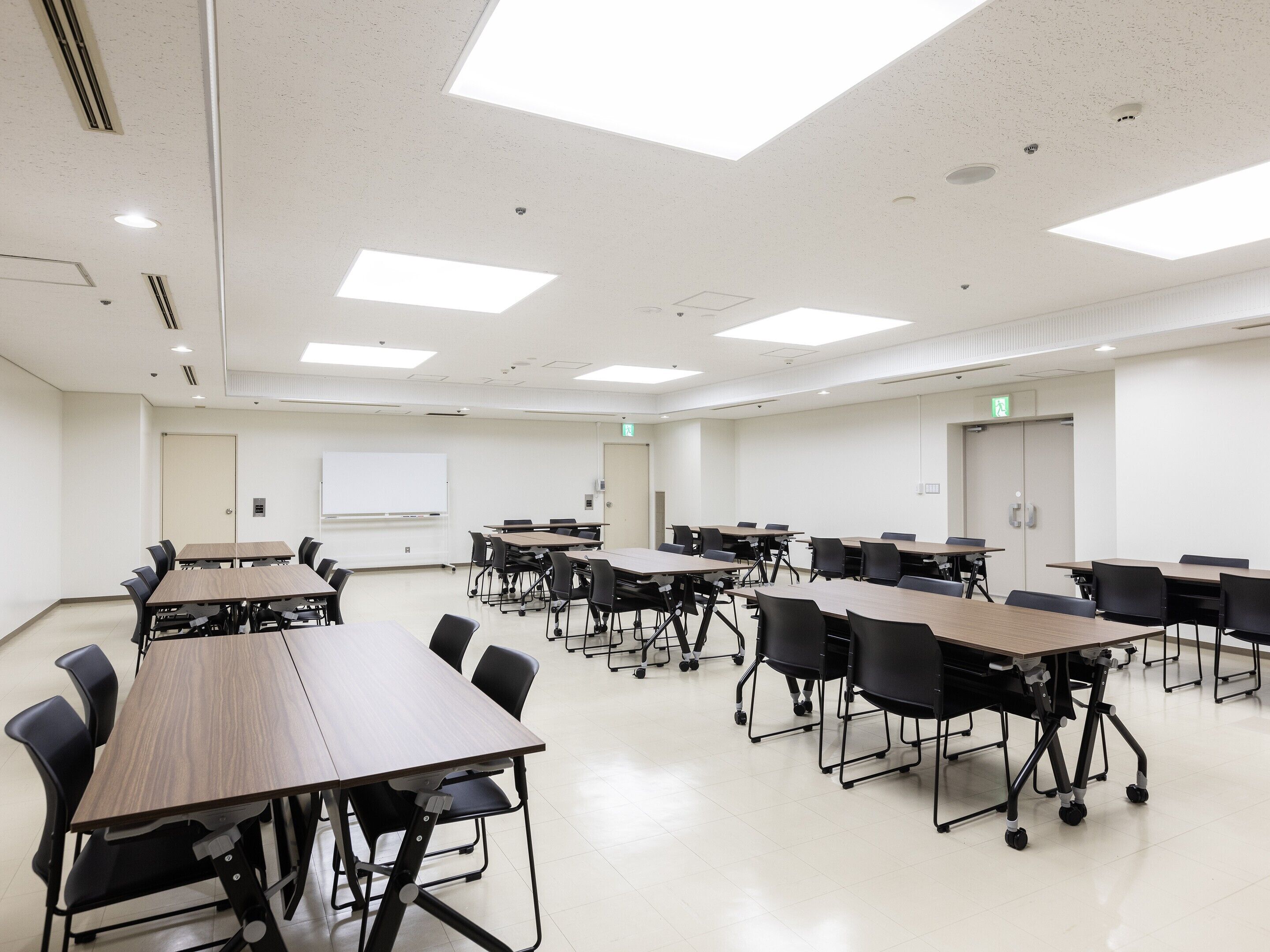 Une salle de conférence dotée de plusieurs tables et chaises, de murs blancs et d’un éclairage au plafond.
