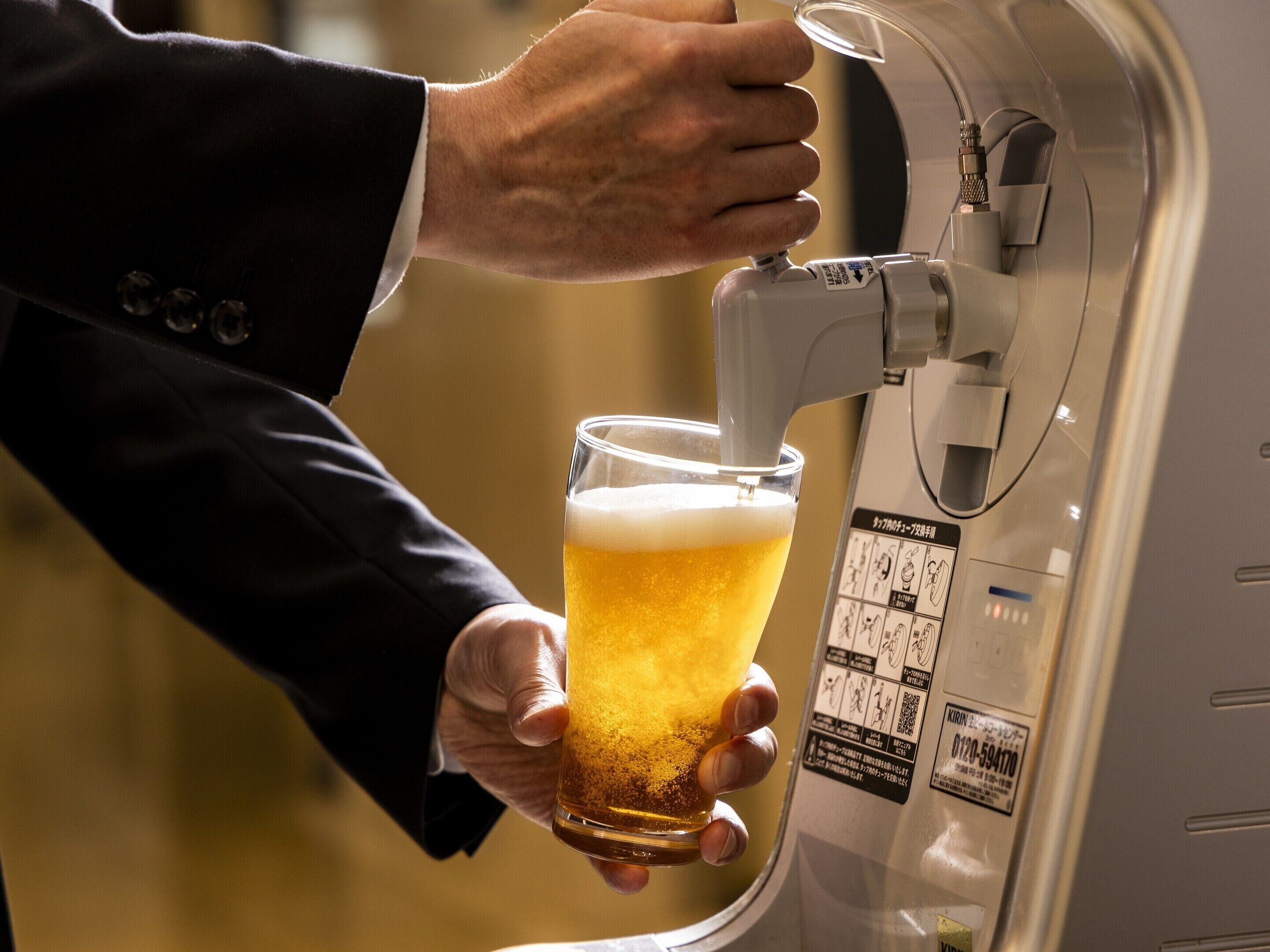 A person holding a glass of beer at a tap.