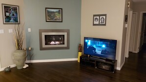 Una sala de estar con chimenea, televisor y cuadros en la pared.