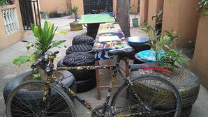 Ein Fahrrad mit einem besonderen Design, ein Tisch mit einer bunten Tischdecke und Blumentöpfe.