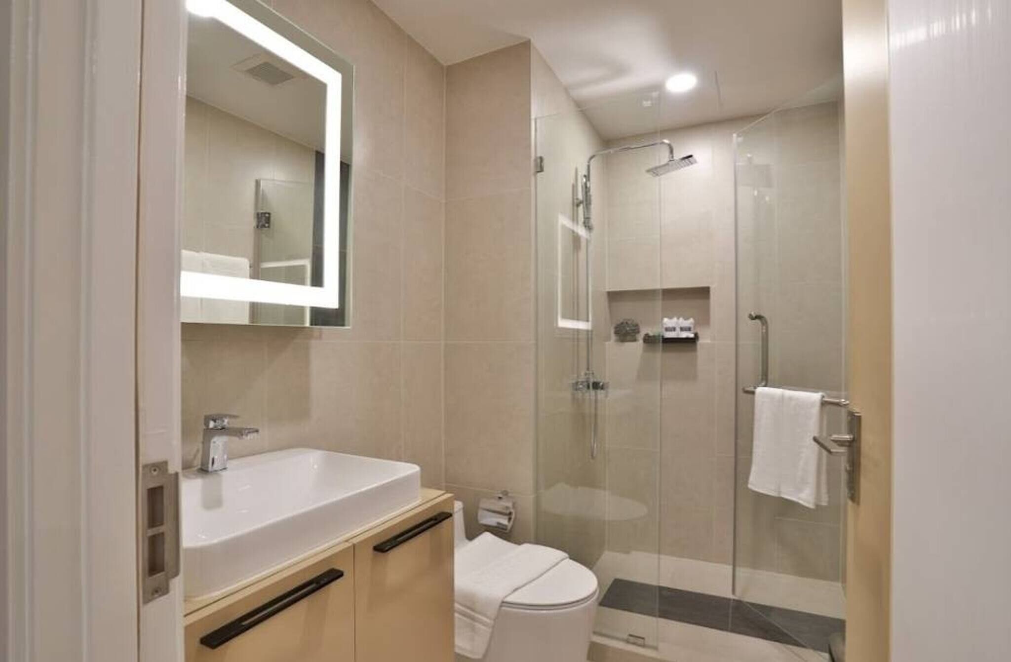 Uma casa de banho moderna com uma grande pia, sanita e área de duche separada por vidro.