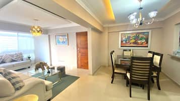 Relax in a spacious living area with a comfortable sofa set, dining table, and decorative chandelier.