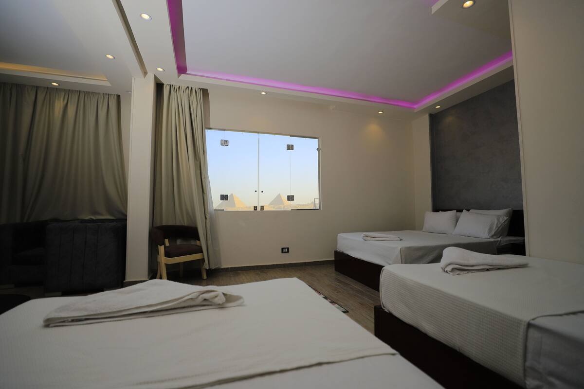A hotel room with two beds, a desk, and a window with a view.