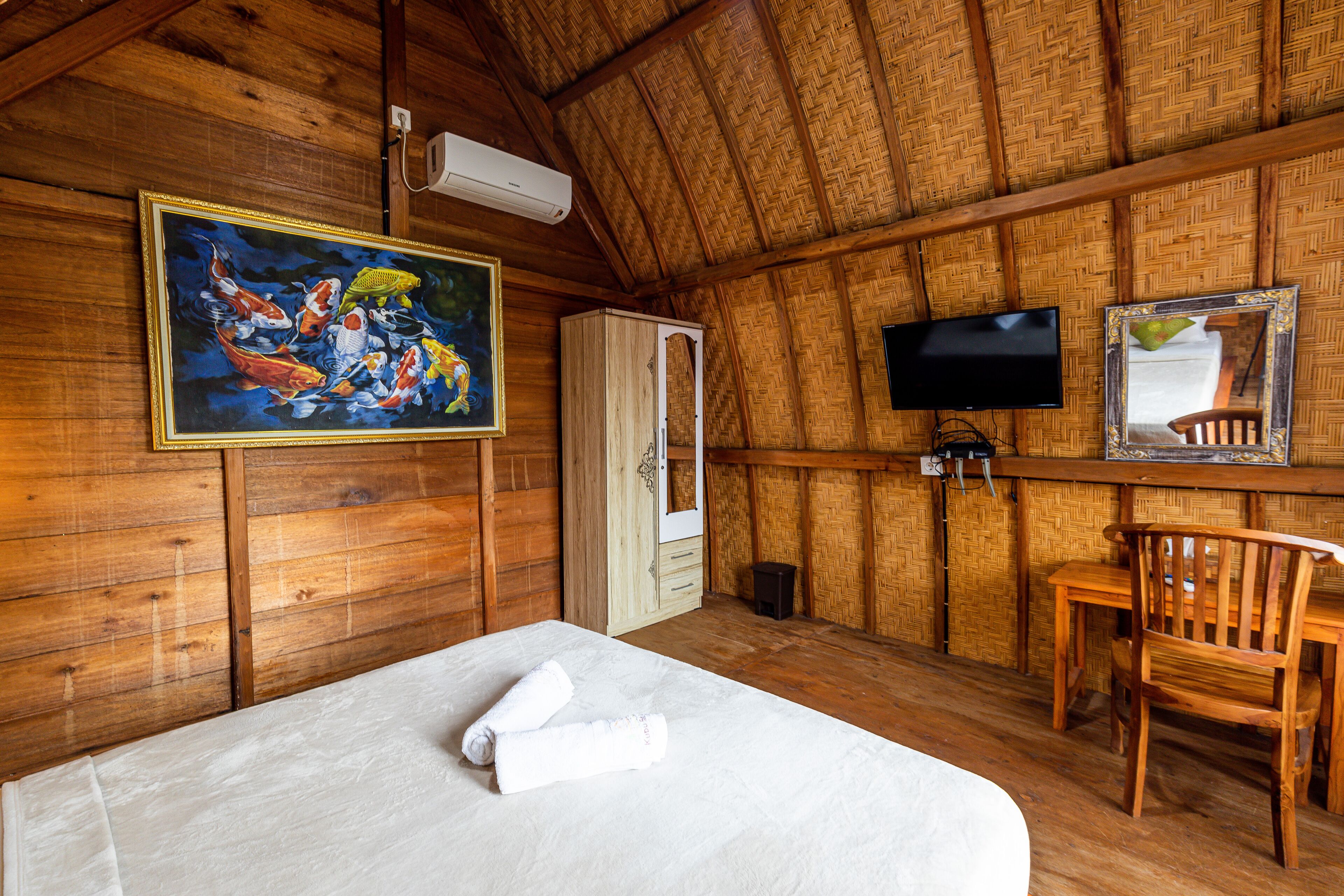 A wooden room with a bed, a painting, a television, and a mirror.