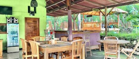 A restaurant with wooden furniture and a covered outdoor seating area.
