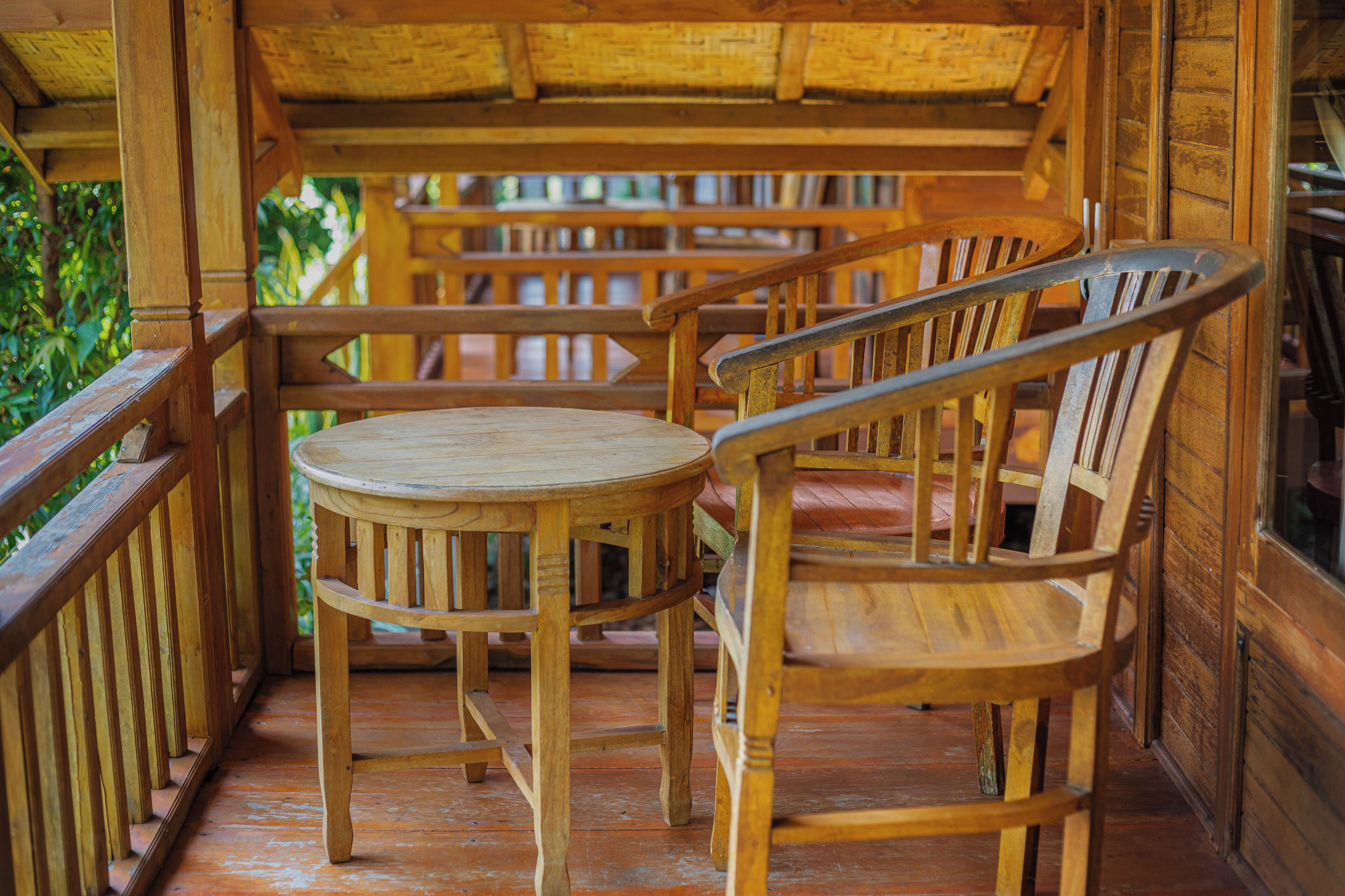 Een houten terras met een ronde tafel en stoelen, omringd door houten leuningen.