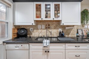 A kitchen with white cabinets, a granite countertop, a Bosch dishwasher, and a fan. - West Texas Manor - Fast Wi-Fi + Game Room by LCH (Midland)