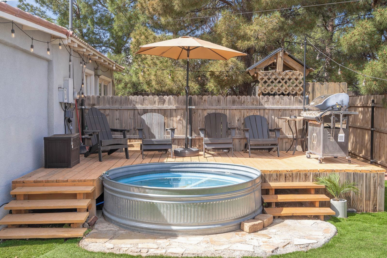 Un jardin avec un jacuzzi, des chaises longues et un barbecue.